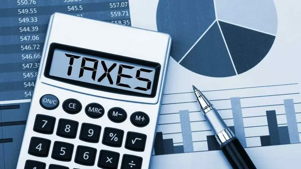 Calculadora sobre planilhas impressas, com a palavra taxas no visor