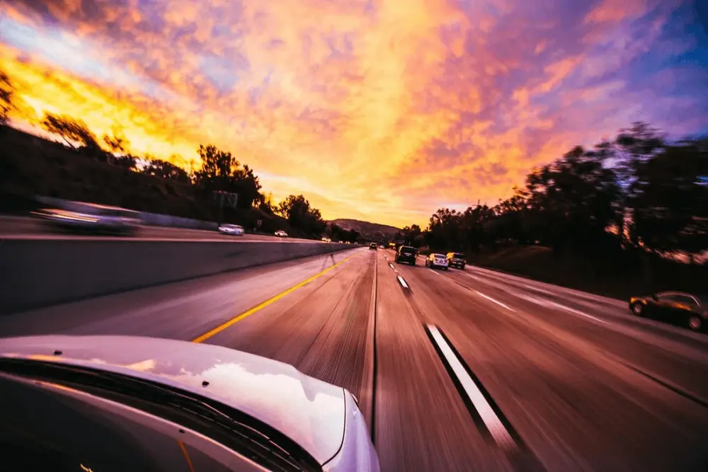 Estrada ao pôr do sol vista de dentro de um carro em movimento